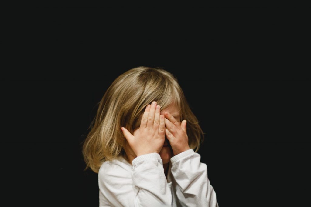 child covering her eyes with her hands